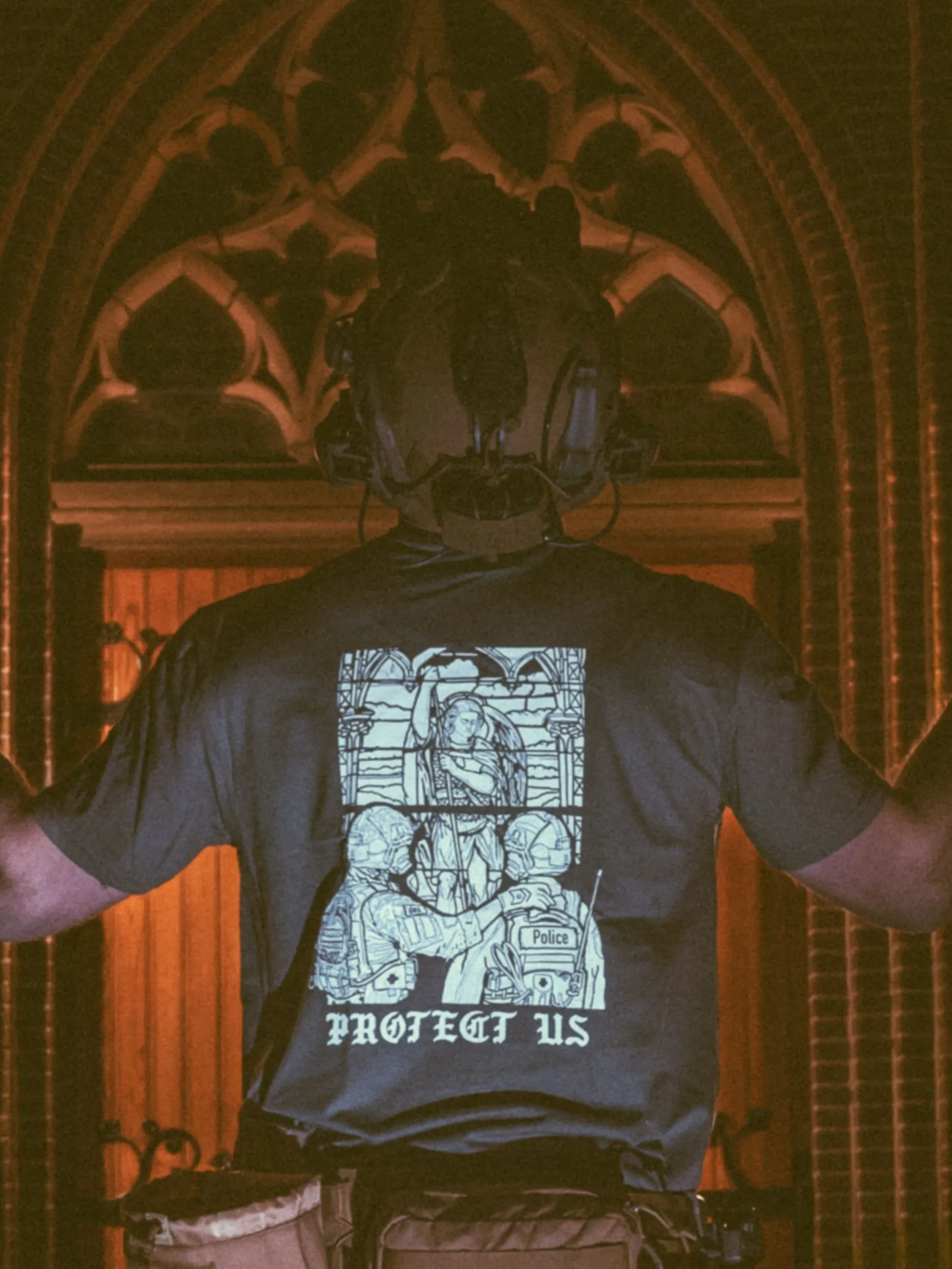 the trace apparel collection featuring a military and a police guy standing in front of a tinted window that displays saint michael the protector